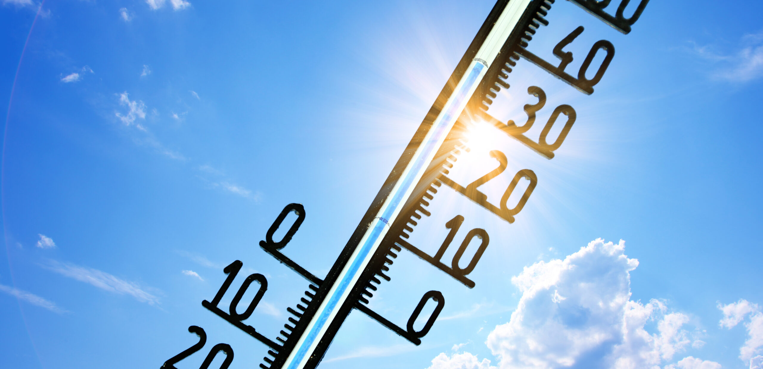 blauer sonniger Himmel, schwarzes Thermometer