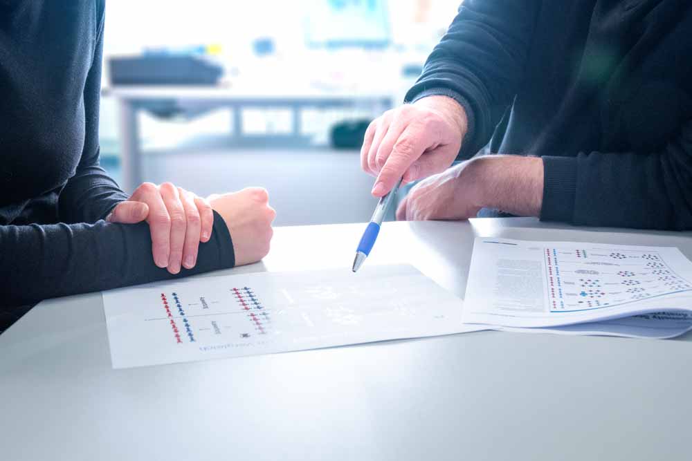 Zwei Personen besprechen auf dem Tisch liegende Papiere mit Diagrammen.