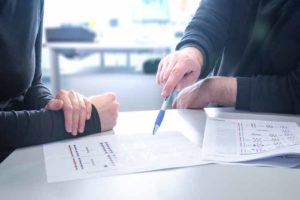 Zwei Personen besprechen auf dem Tisch liegende Papiere mit Diagrammen.